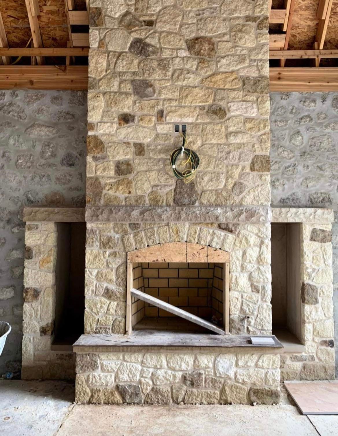 A large stone fireplace is being built in a room.