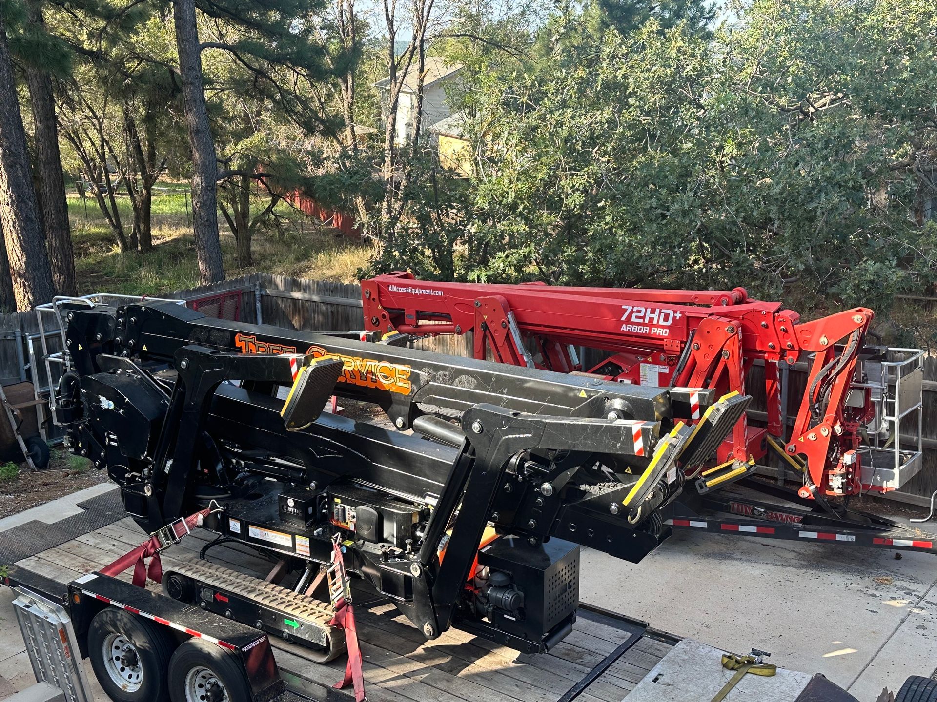 Red and black heavy-duty construction machinery parked outdoors among trees and equipment