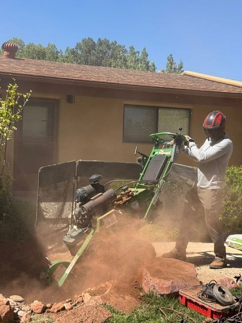Person in helmet operating a green off-road vehicle as it flips in a dusty yard near a house