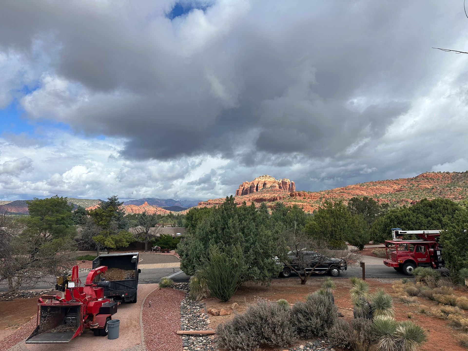 Red truck in a desert campground with cloudy sky and red rock cliffs in the distance