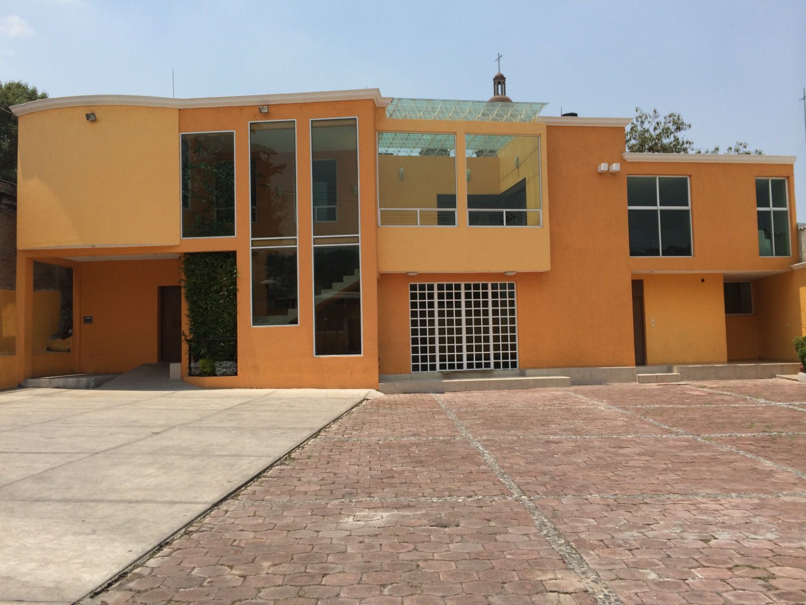 Una casa grande de color naranja con una entrada de ladrillos al frente.