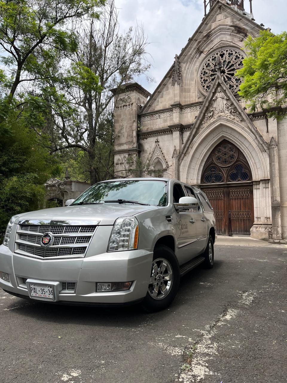 Un Cadillac Escalade plateado está estacionado frente a una iglesia.