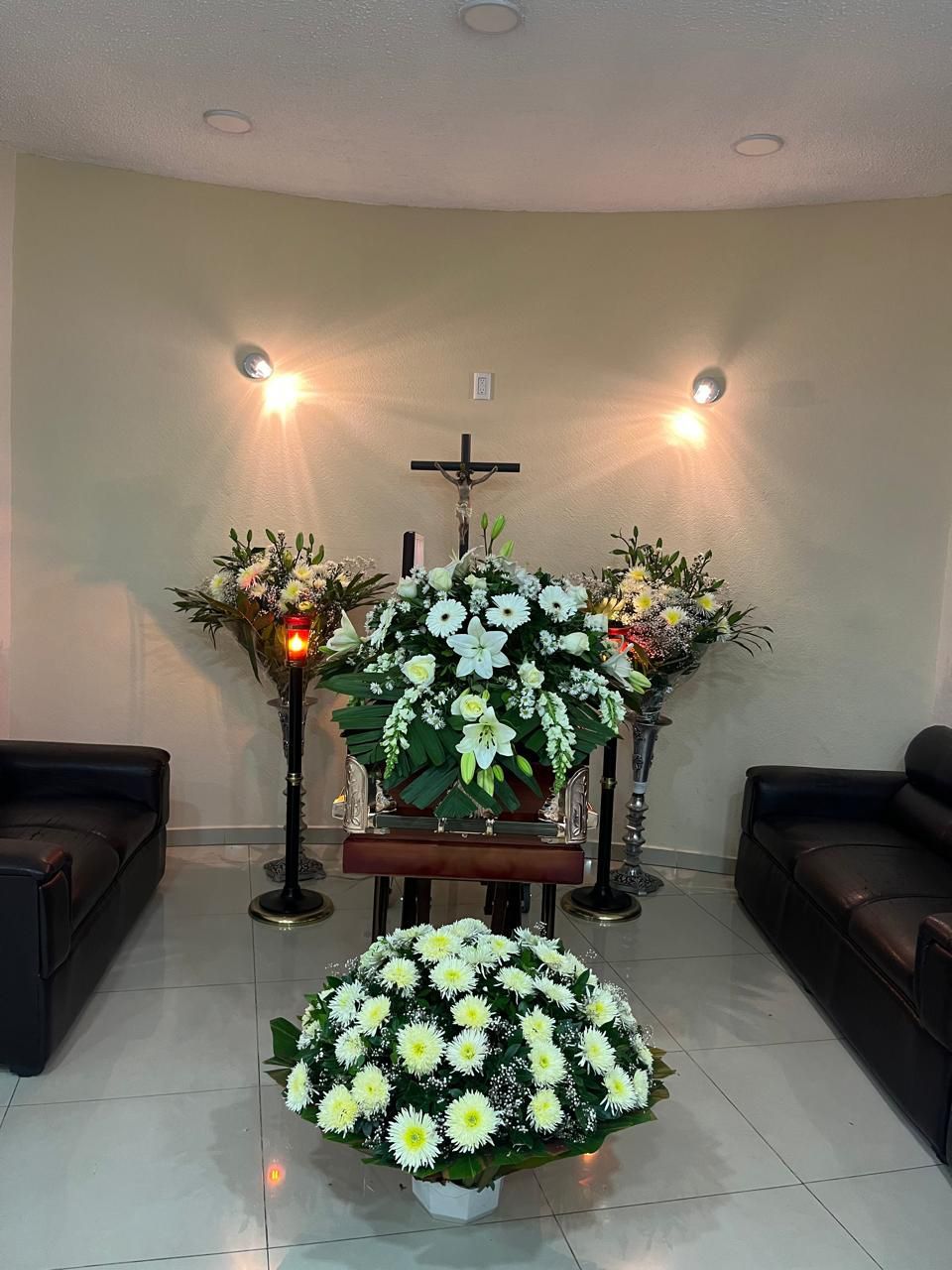 Una habitación con flores y una cruz en la pared.