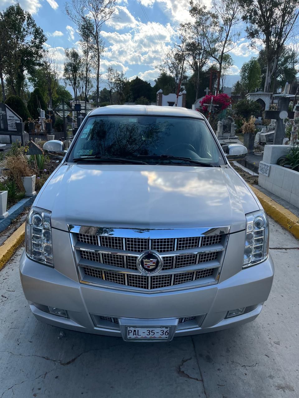 Un Cadillac Escalade plateado está estacionado en un cementerio.