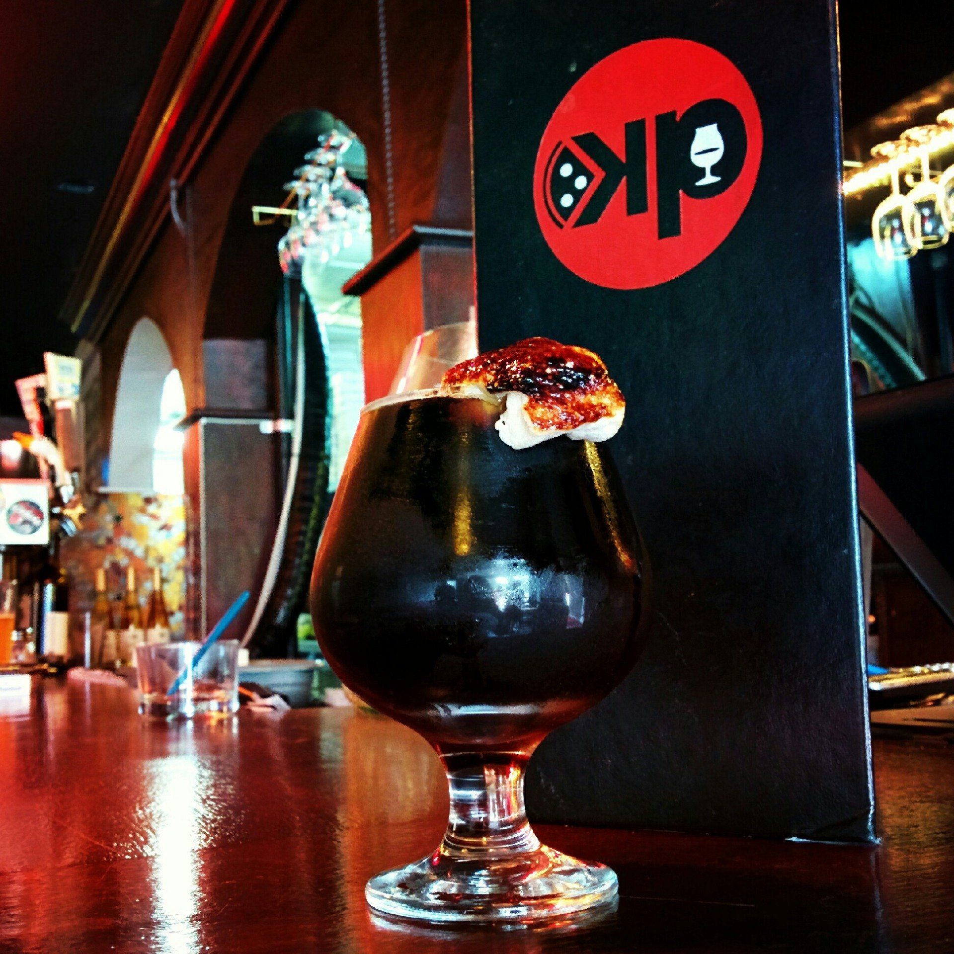 A drink in a glass next to a menu that says KP
