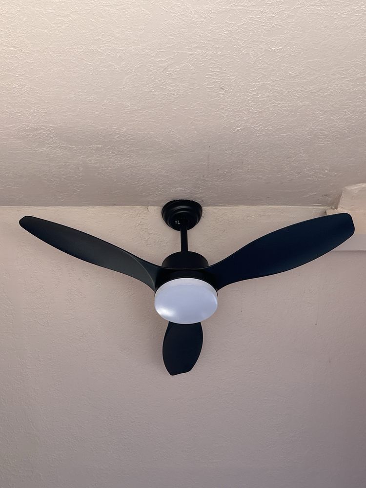 A black ceiling fan with three blades is hanging from the ceiling.
