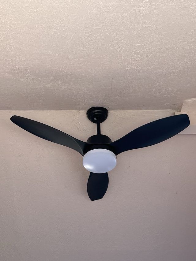 A black ceiling fan with three blades is hanging from the ceiling.