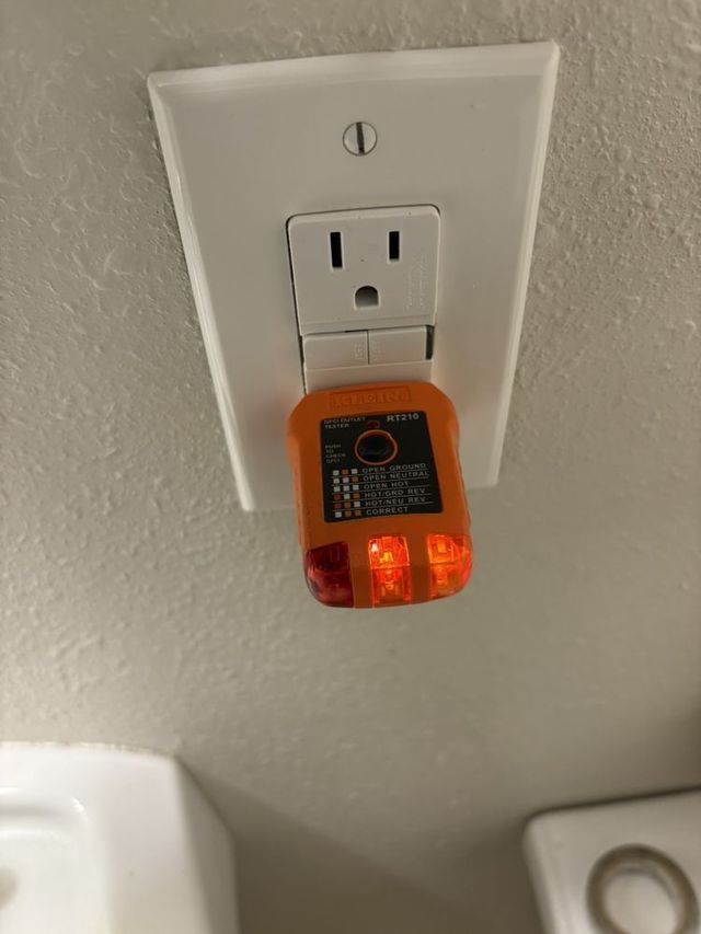 An orange device is plugged into a white electrical outlet.