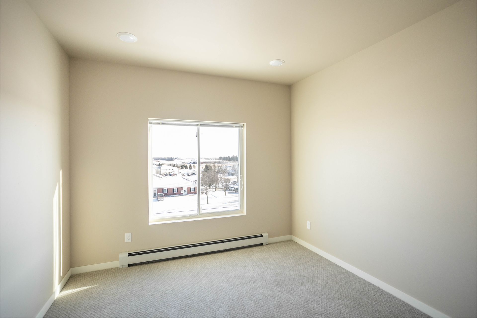 An empty room with a window and a sliding glass door.