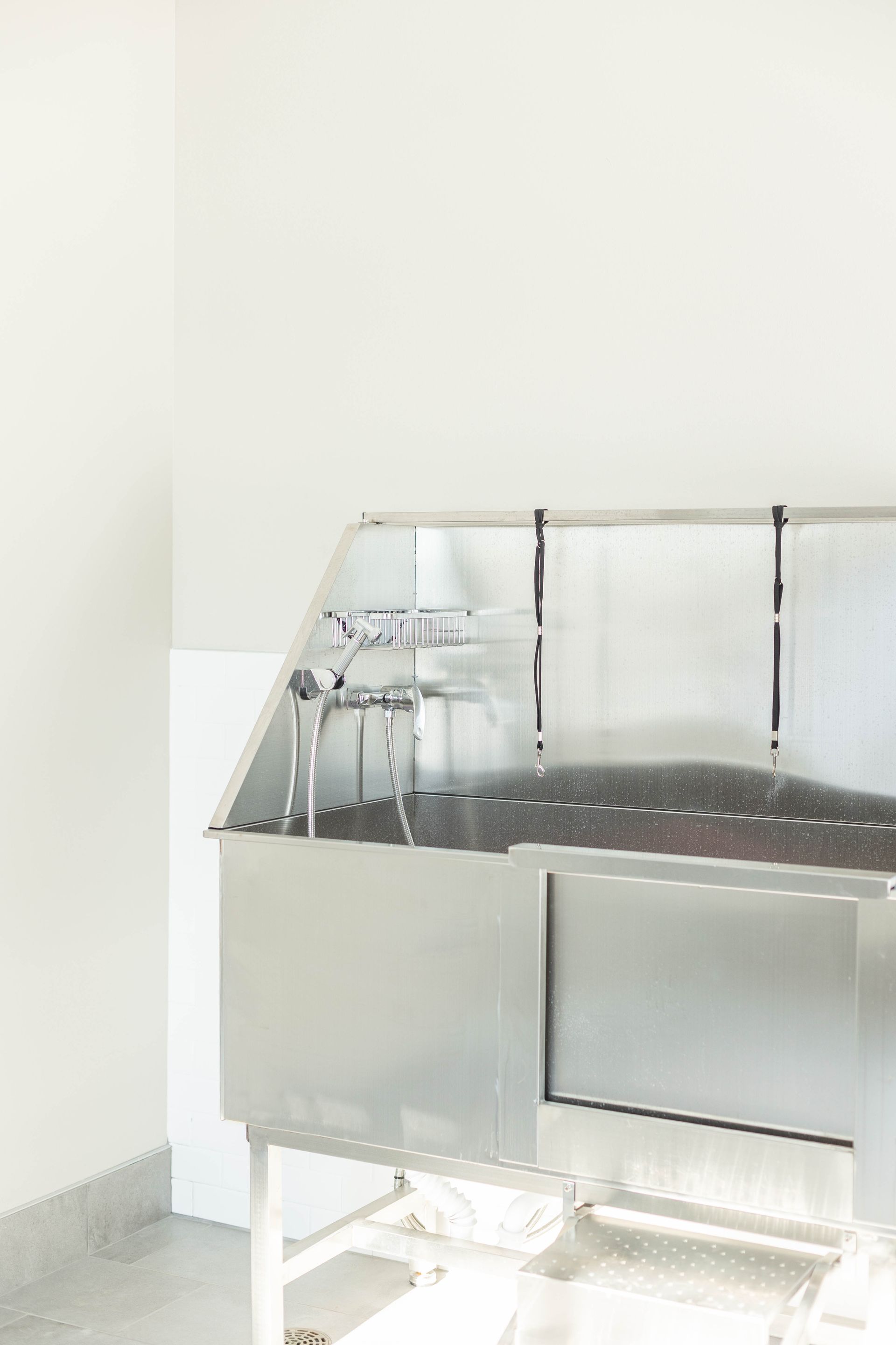 A stainless steel sink in a room with a white wall.
