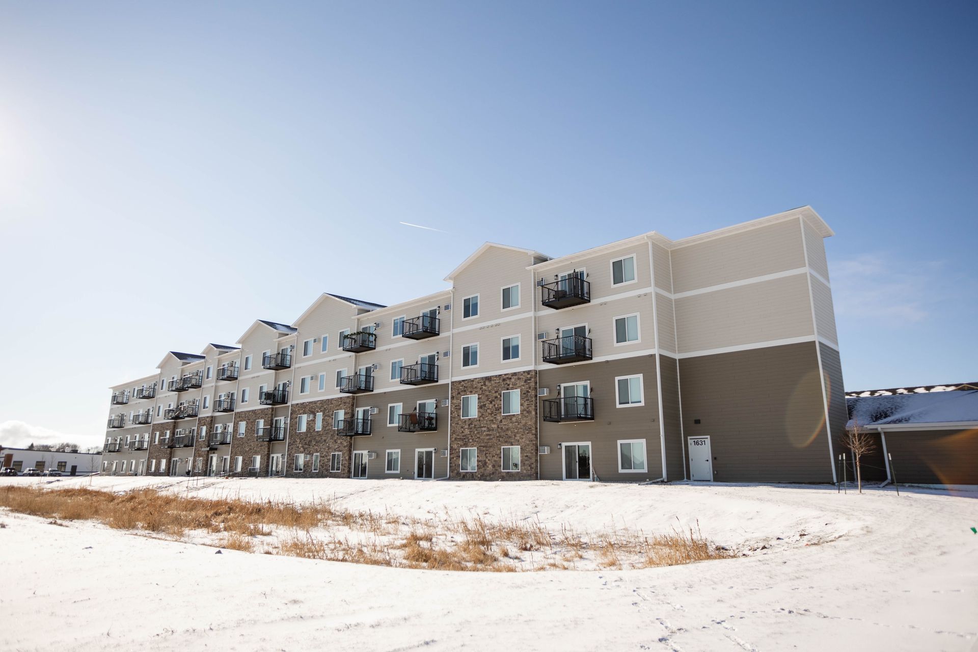 A large apartment building with snow on the ground in front of it