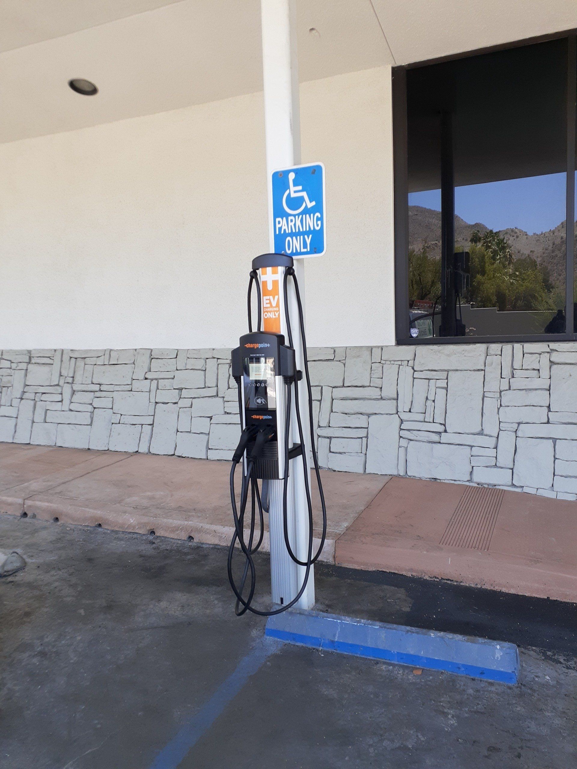 Electric vehicle charging station with wheelchair parking sign.