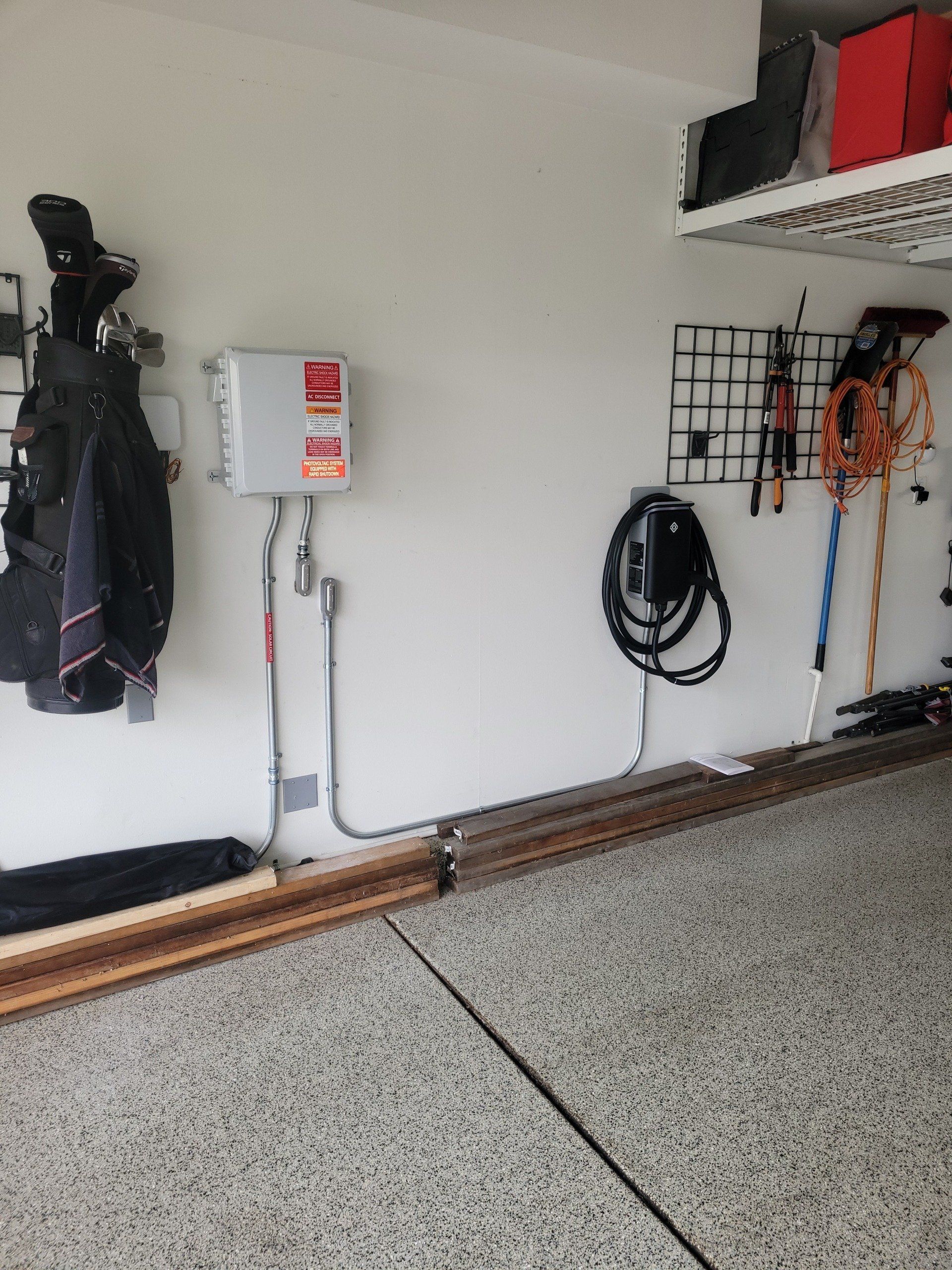 Garage interior with EV charger, storage, and an electrical box on the wall.