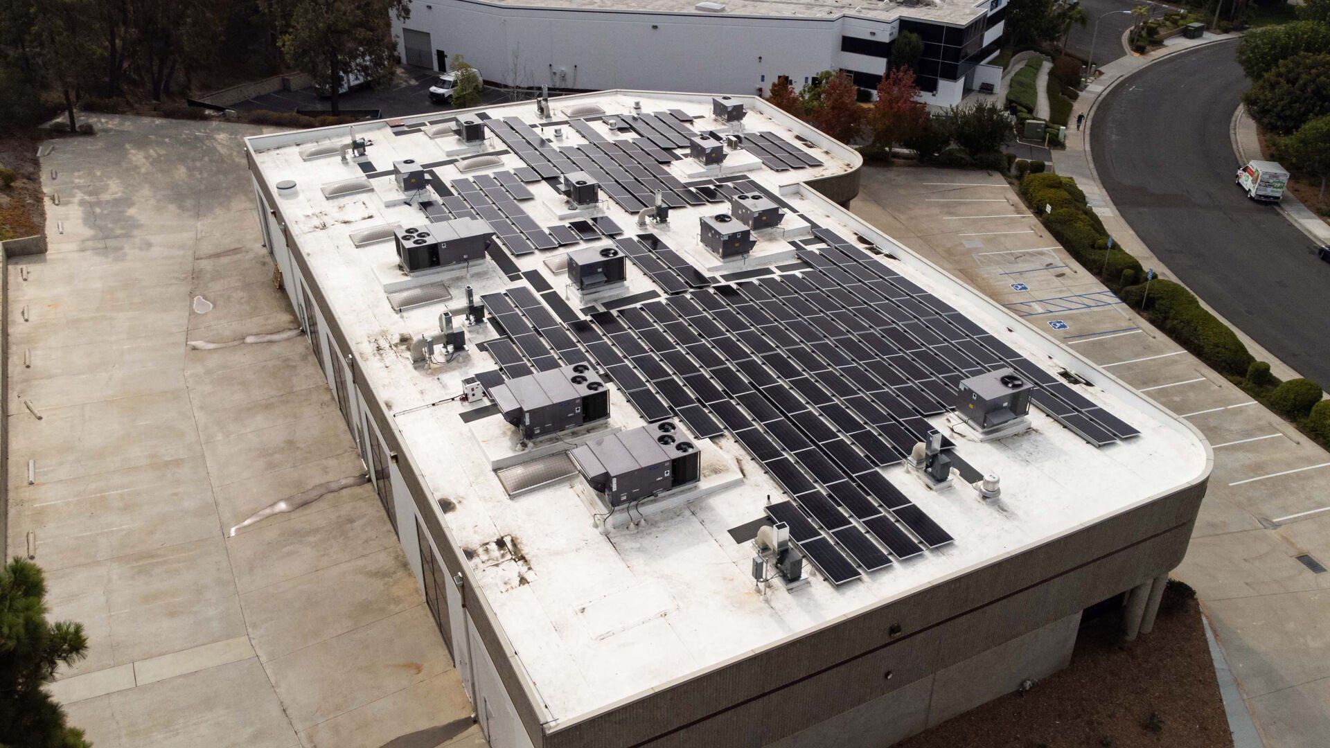 Solar panels installed on a commercial building's flat roof; daytime shot.