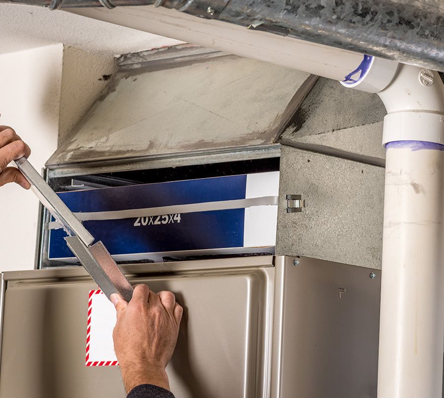 Person replacing an air filter in an HVAC system. The filter is blue, and the ductwork is gray.
