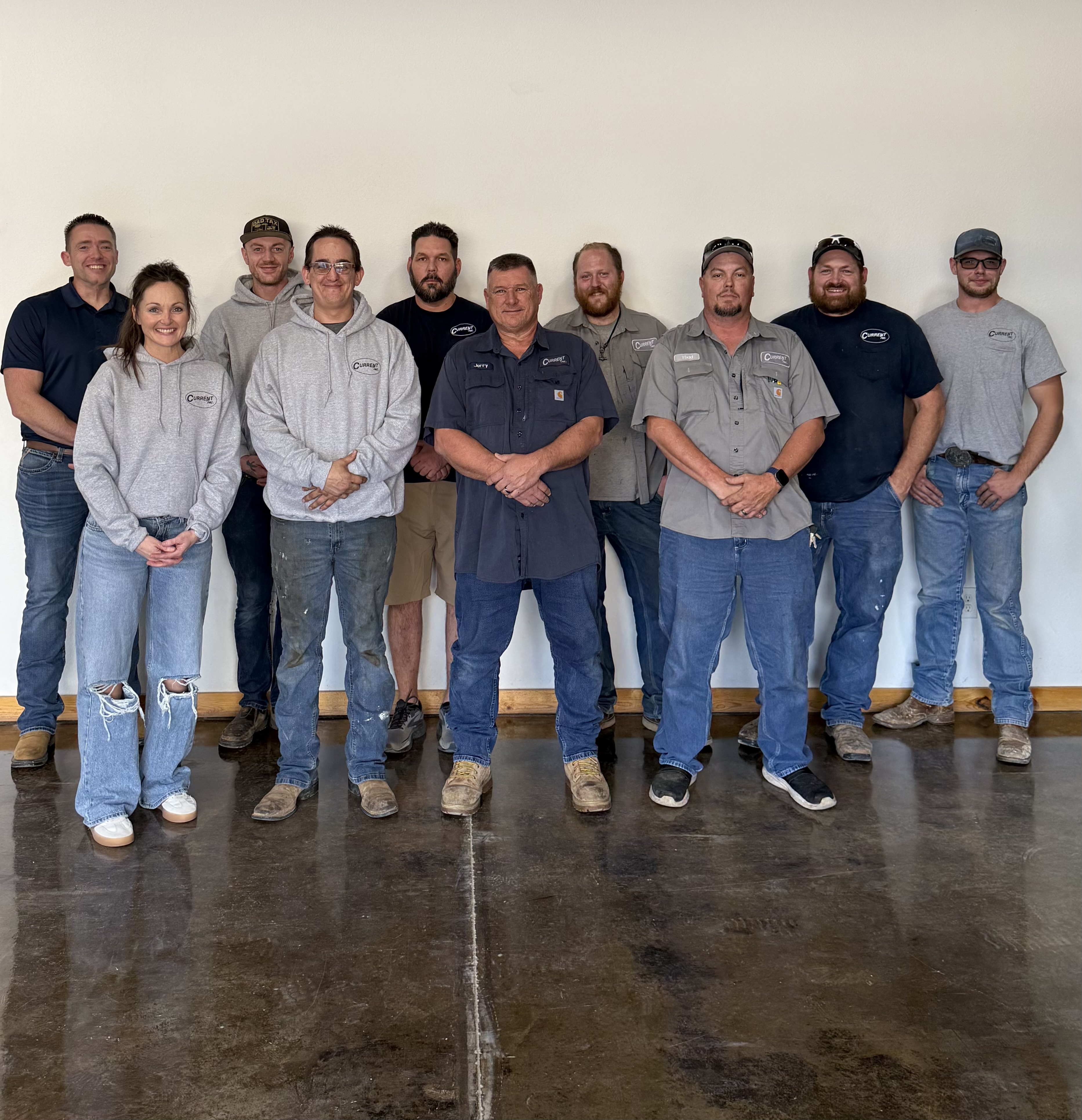 HVAC technician on a rooftop repairs an air conditioning unit using a power drill.