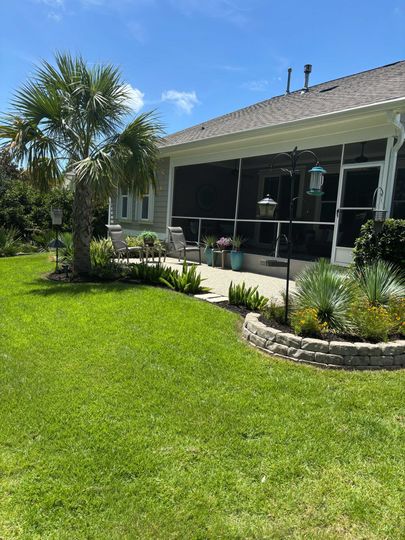 Sunny suburban house with screened porch, green lawn, and a palm tree in front yard