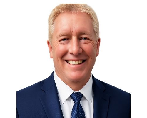 Smiling man in a navy suit and blue tie against a white background