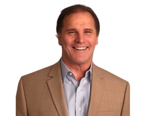 Smiling man in a tan blazer and light blue shirt against a white background