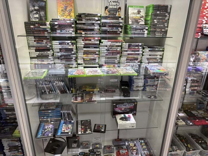 A glass display case filled with video games for sale in a store.
