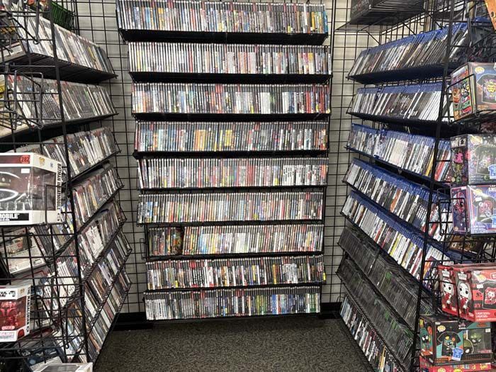 Shelves packed with video games in a store, creating a dense, varied collection.