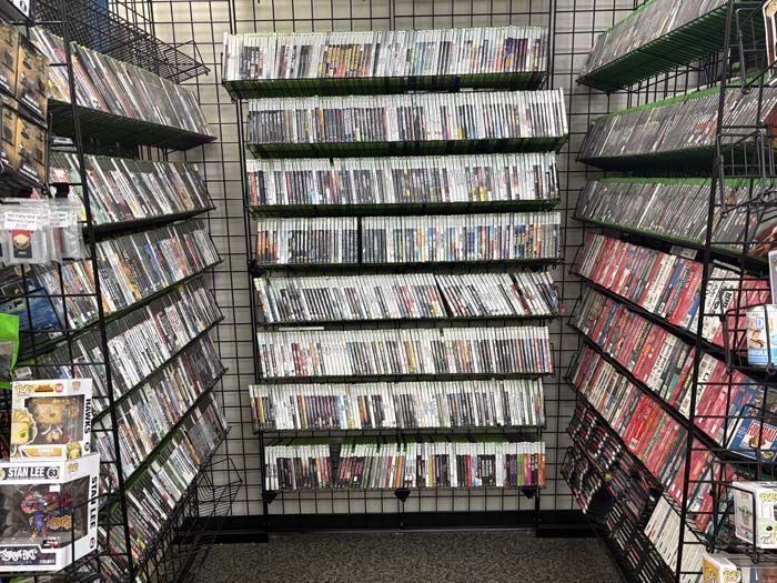 Shelves of video games in a store, white and black game cases in rows.