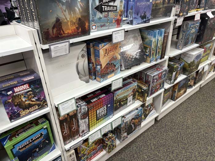 Shelves displaying board games in a store. Boxes of various sizes and colors are visible.