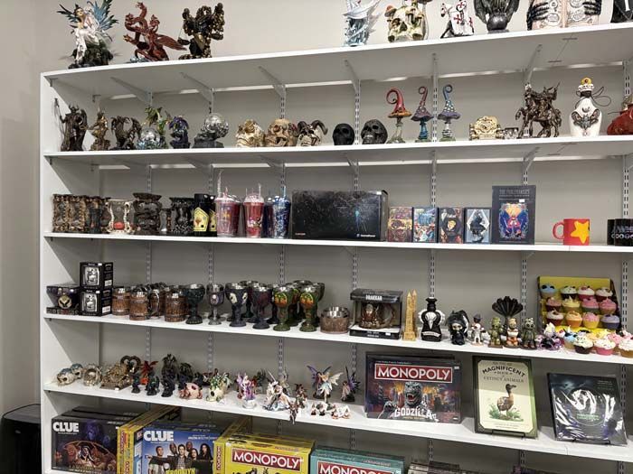 White shelving unit displaying various figurines, games, and collectibles in a well-lit room.