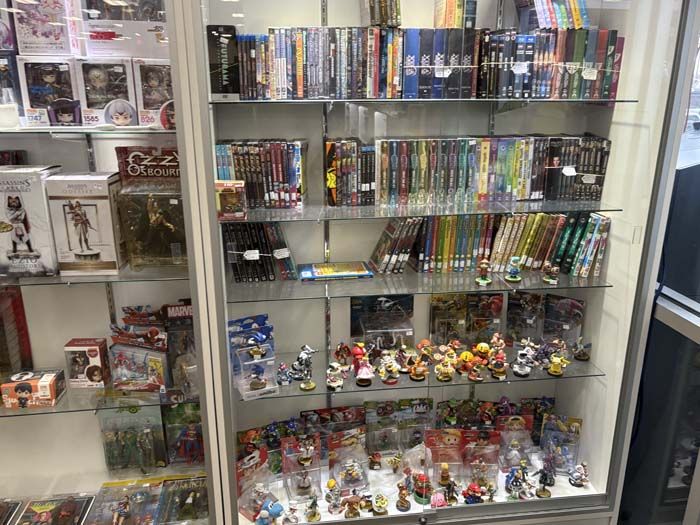 Glass display case in a store filled with video games, figurines, and DVDs.