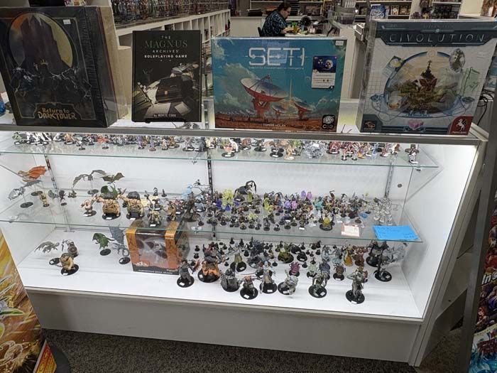 Display case in a game store with board games and figurines.