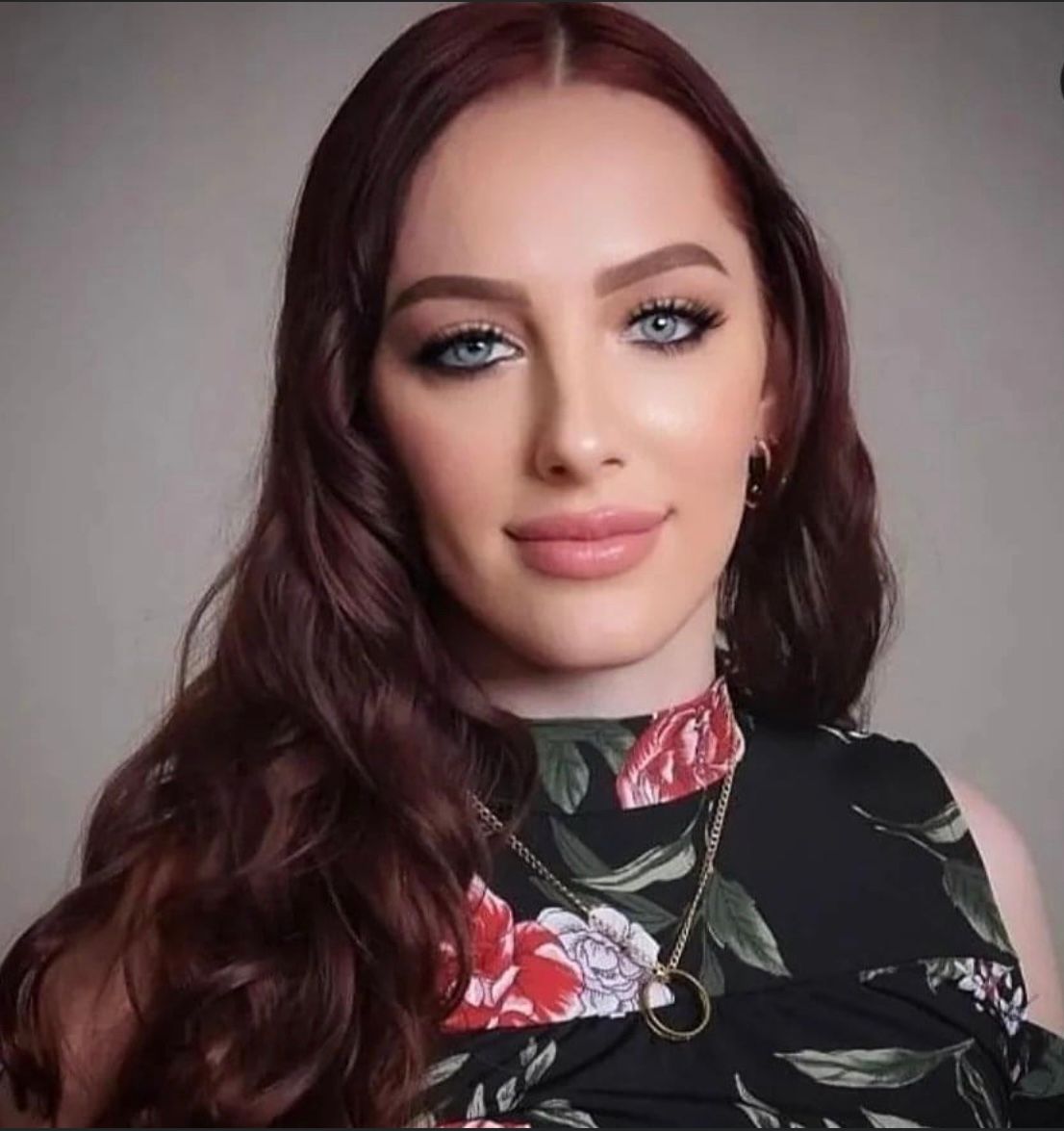 A woman with long red hair is wearing a floral dress