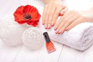 Beauty and Personal Care A woman 's hands are sitting on a towel next to a bottle of nail polish.