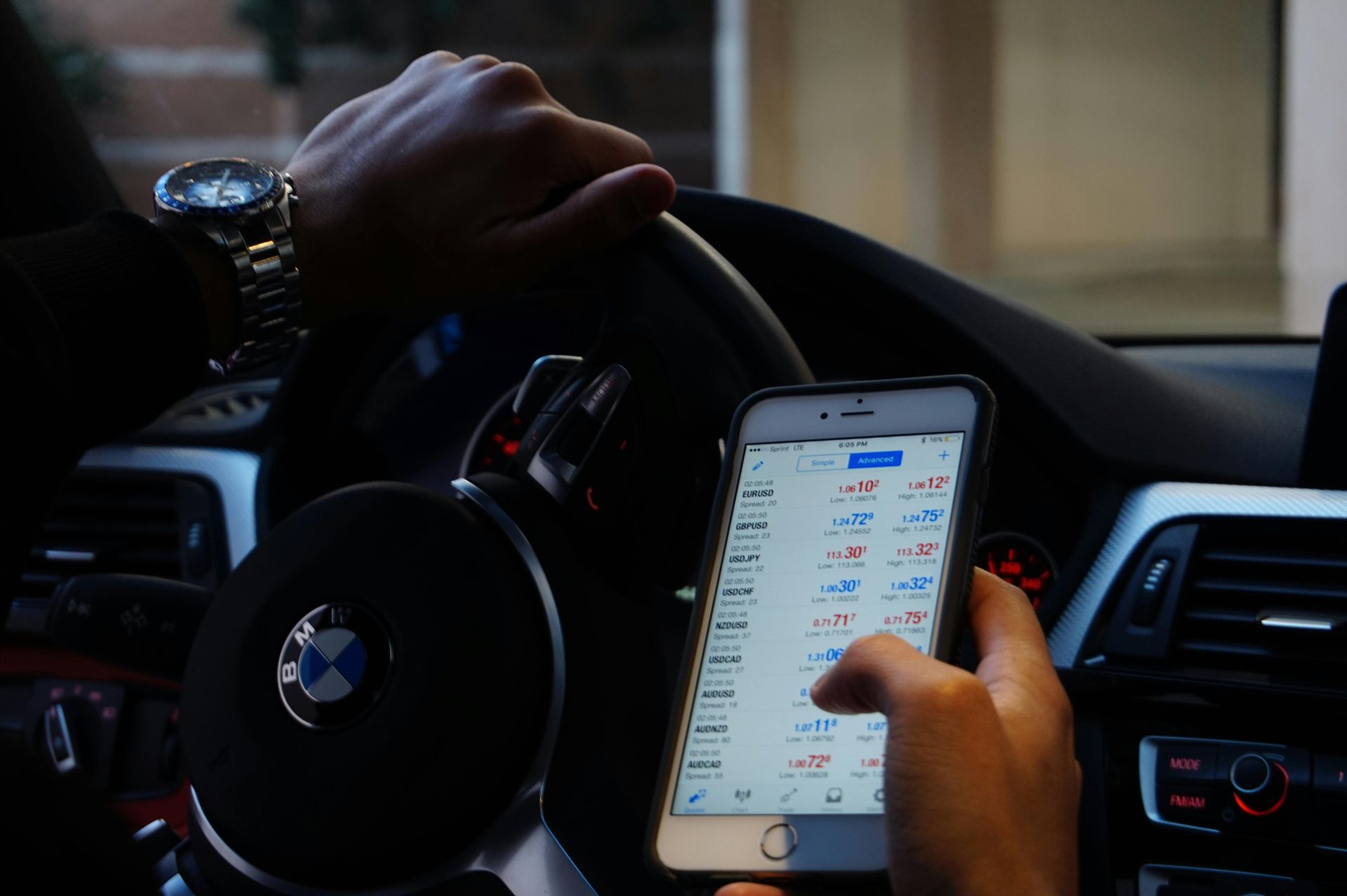 A person is holding a cell phone in their hand while driving a car.