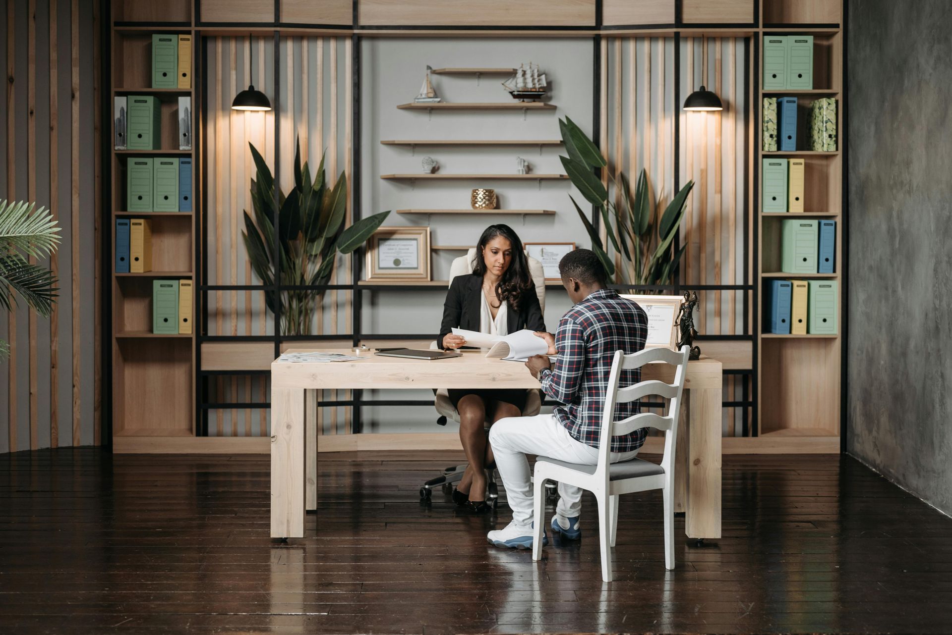 A woman is sitting at a desk talking to a man.