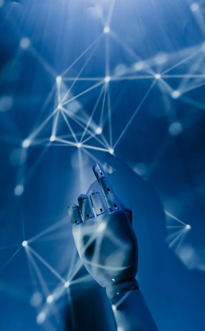 A robotic hand is holding a cell phone in front of a blue background.