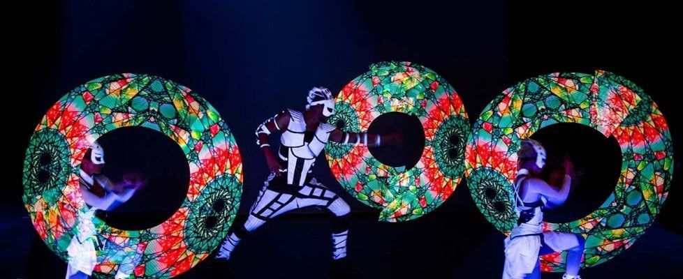 Un gruppo di persone tiene in mano delle ghirlande luminose al buio.