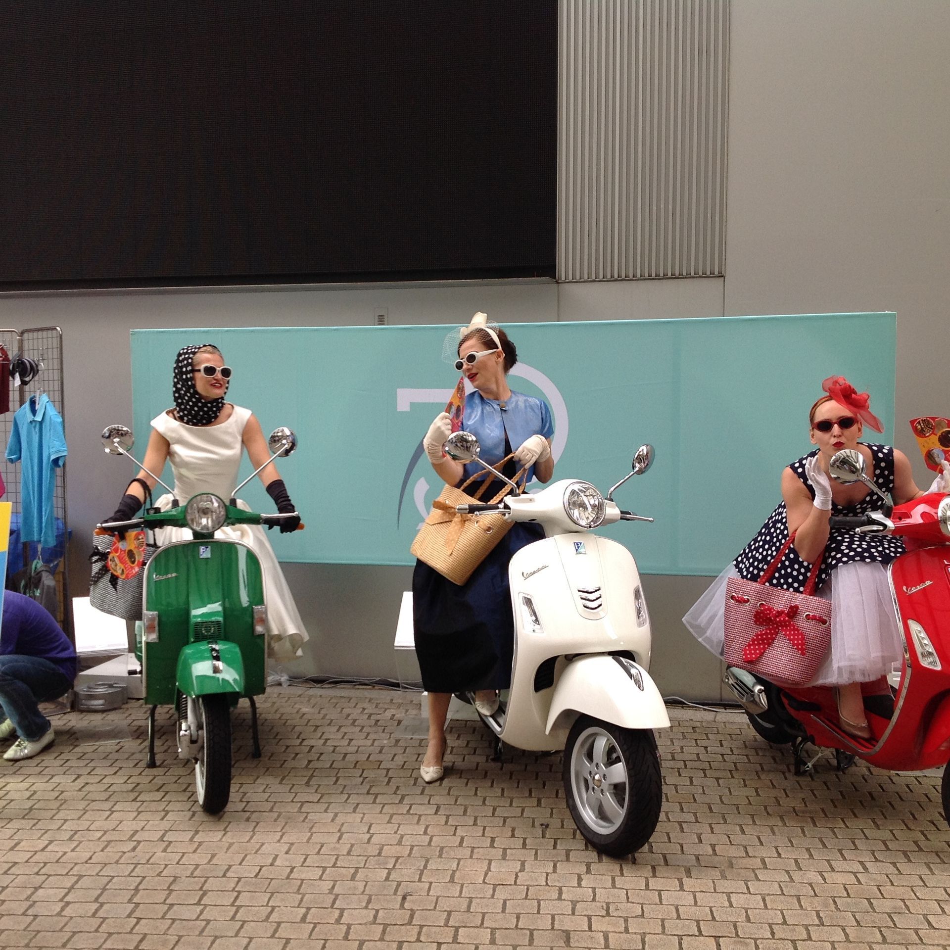 Un gruppo di donne guida gli scooter davanti a un muro con il numero 7