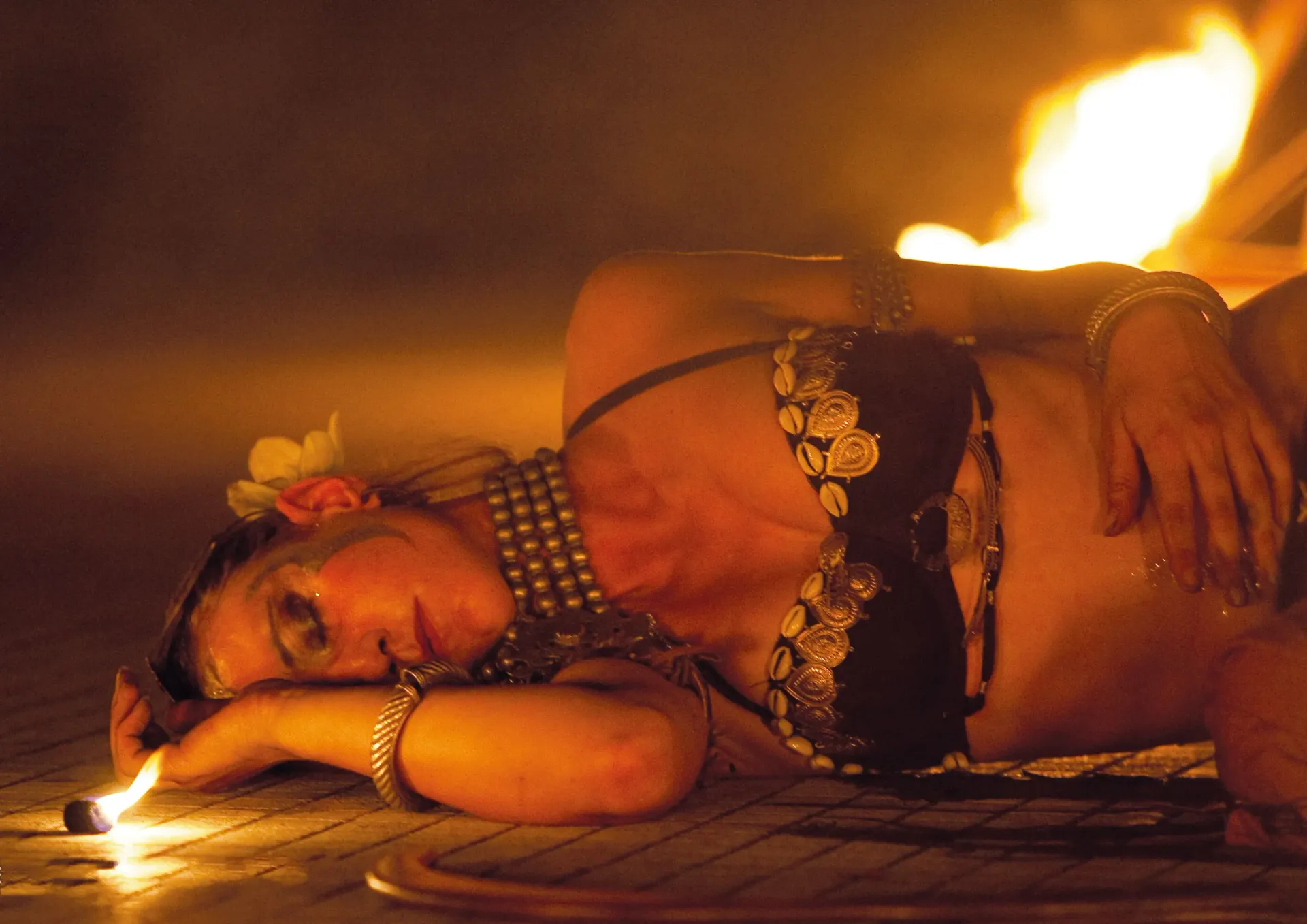 Una donna è sdraiata sul pavimento con una candela in mano.
