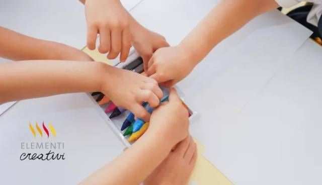 Un gruppo di bambini sta giocando con i pastelli sul pavimento.