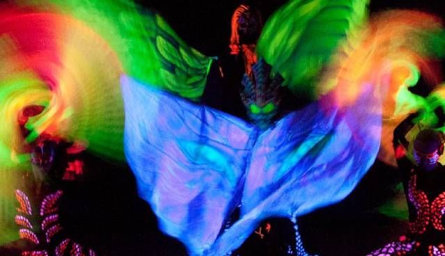 Una persona sta ballando davanti a uno sfondo luminoso al buio.