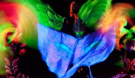 Una persona sta ballando davanti a uno sfondo luminoso al buio.