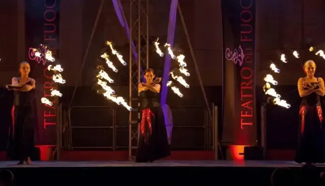 Un gruppo di donne sta eseguendo uno spettacolo di fuoco su un palco.