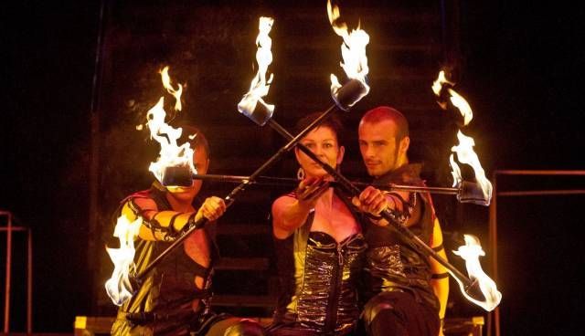 Un gruppo di persone sta suonando dei violini dai quali escono delle fiamme.