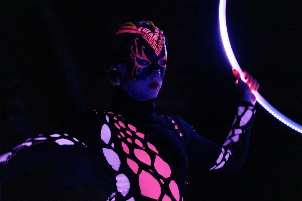 Una donna tiene in mano un cerchio di hula hoop luminoso al buio.