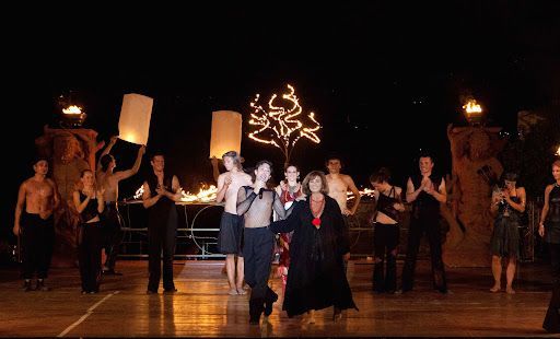 Un gruppo di persone sta ballando su un palco di notte.