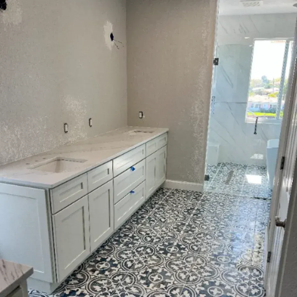Bathroom with white vanity, patterned black-and-white tile floor, and glass shower enclosure.