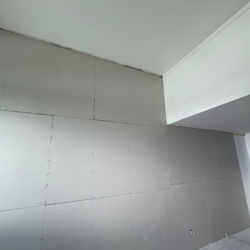 Gray drywall panels installed on an interior wall and ceiling corner during renovation