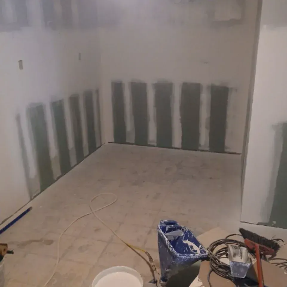 Unfinished room with tiled floor, white walls, and construction tools and materials scattered on the floor.