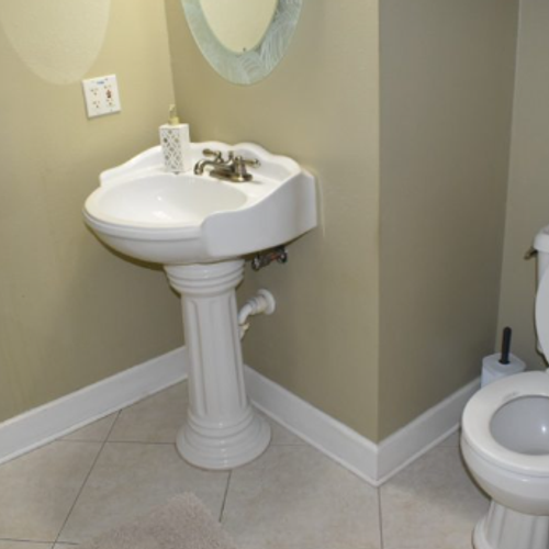 Small beige bathroom with a white pedestal sink and partial view of a toilet.