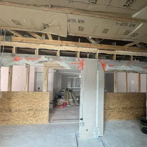 Partially renovated interior with exposed framing, drywall, and an open hallway under construction